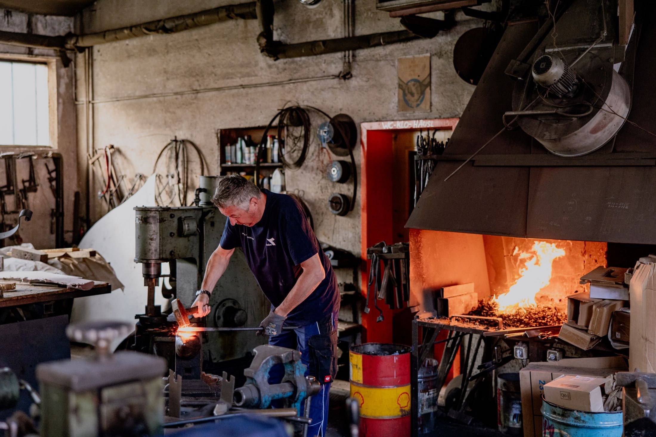 Ein Schmied arbeitet in einer Werkstatt mit einem brennenden Schmiedefeuer.