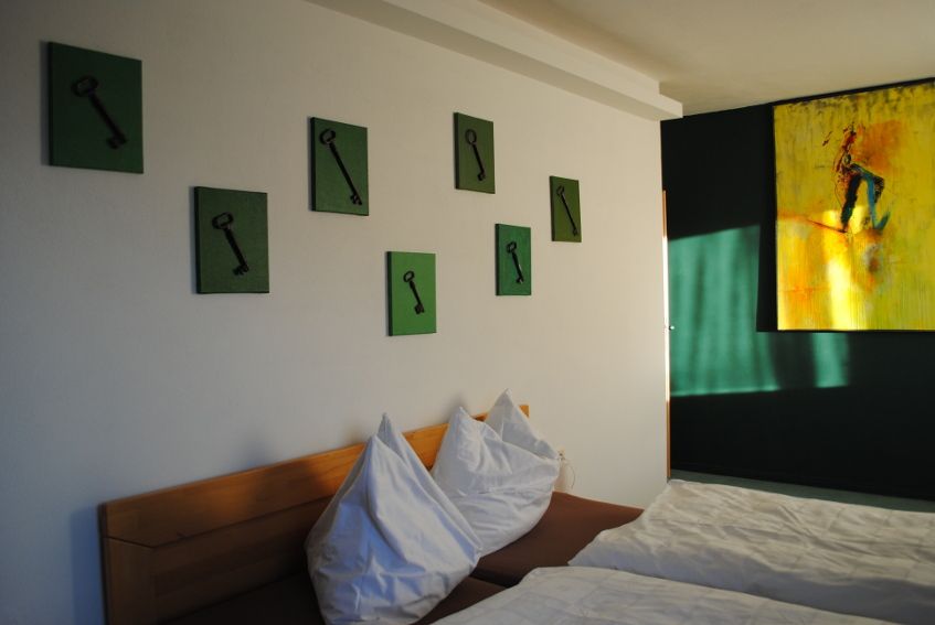 Ein Zimmer mit zwei Betten, grünen Bildern von Schlüsseln an der Wand und einem gelben Gemälde.