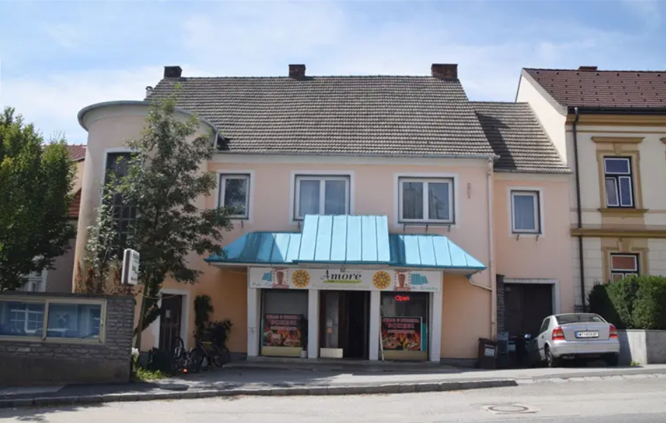 Ein kleines Restaurant mit blauer Markise und einem Auto davor.