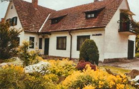 Ein weißes Haus mit rotem Ziegeldach und Garten voller gelber Blumen.