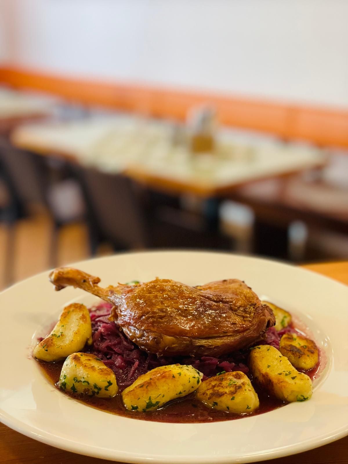 Teller mit gebratener Entenkeule, Kartoffelklößen und Rotkohl in einem Restaurant.