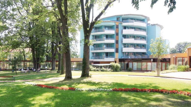 Modernes Geb&auml;ude mit Balkonen und Garten im Vordergrund.