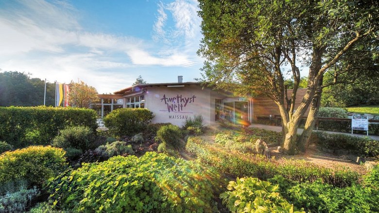 Eingang zur Amethyst Welt Maissau mit Garten und B&auml;umen im Vordergrund.