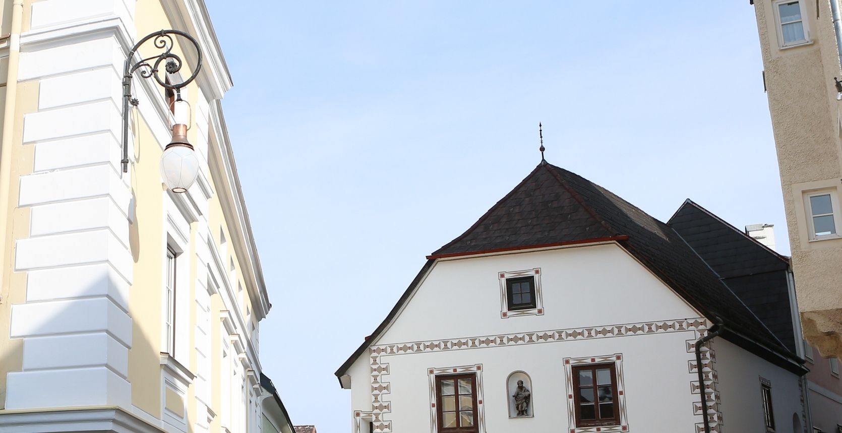 Historische Straßenlaterne an einem Gebäude in einer Altstadt.