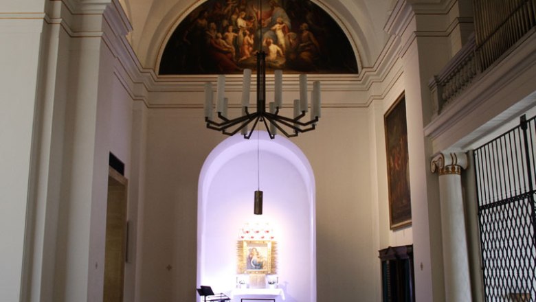 Innenansicht einer Kirche mit Altar und Gemälde an der Wand.