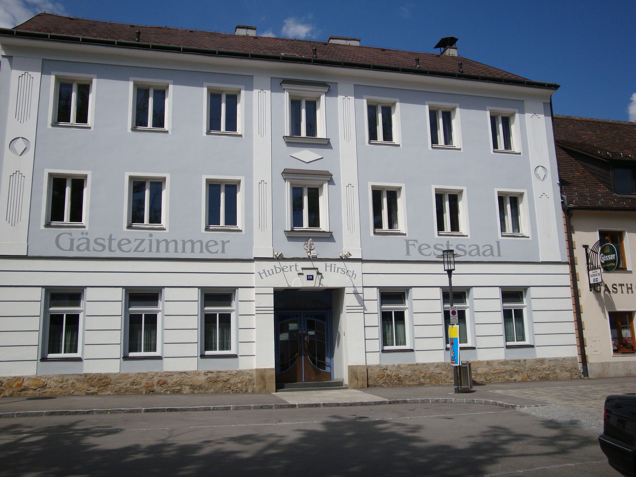 Fassade eines Gasthauses mit der Aufschrift 'Gästezimmer' und 'Festsaal'.