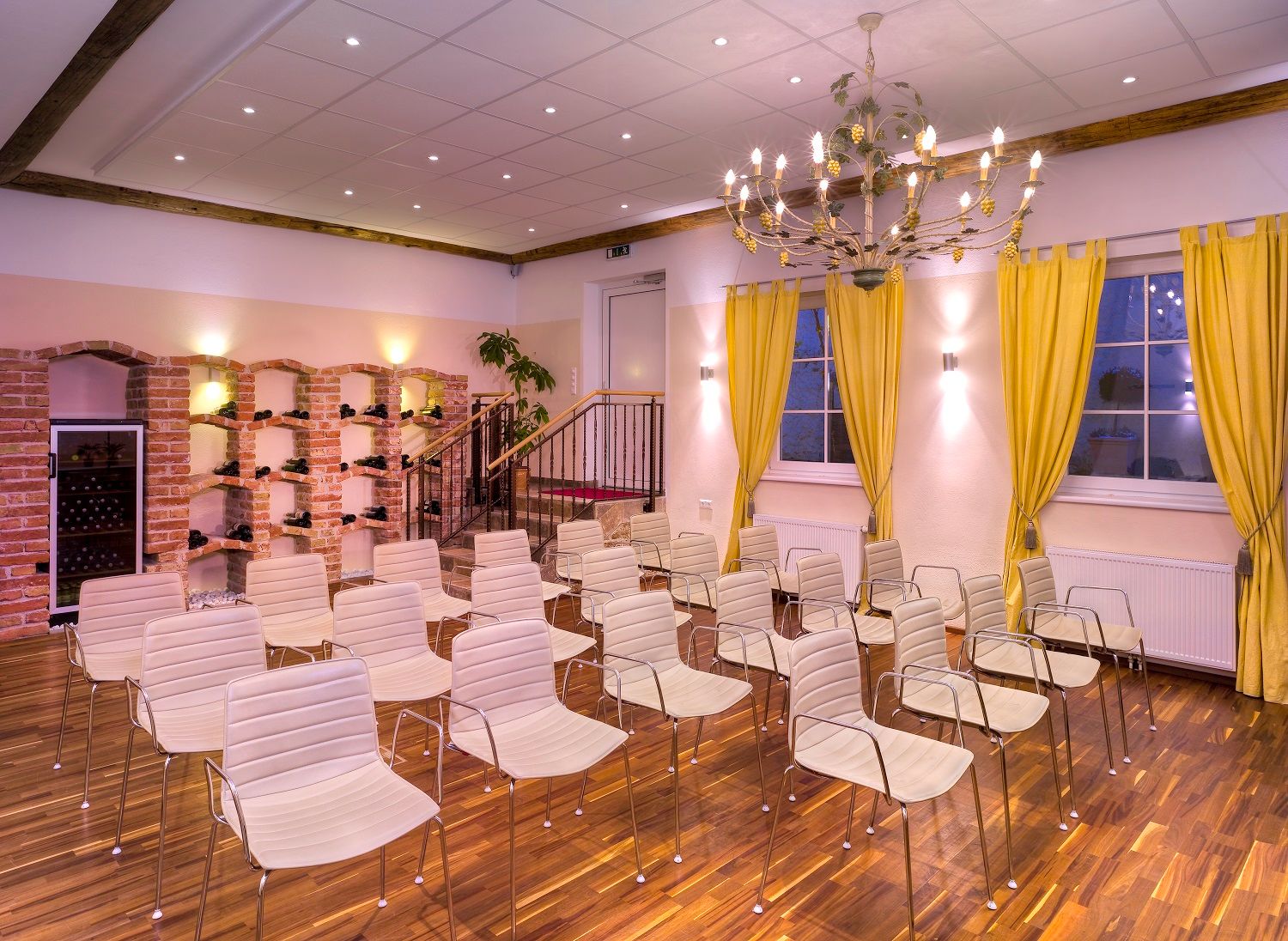 Ein Konferenzraum mit weißen Stühlen, gelben Vorhängen und einem Kronleuchter.