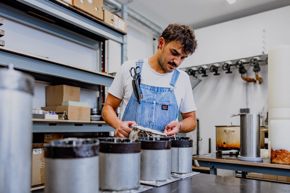Mann in Werkstatt zieht Kerzen in Metallformen.