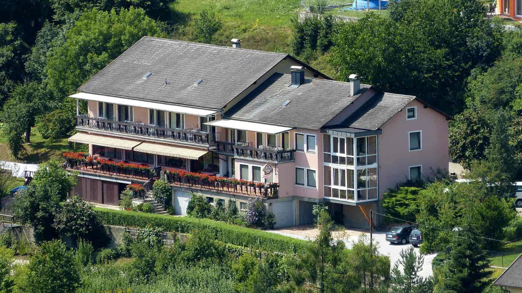 Großes Haus mit Balkon und Garten, umgeben von Bäumen.