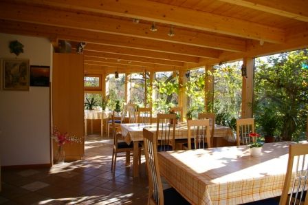 Heller Wintergarten mit Holzmöbeln und Pflanzen.