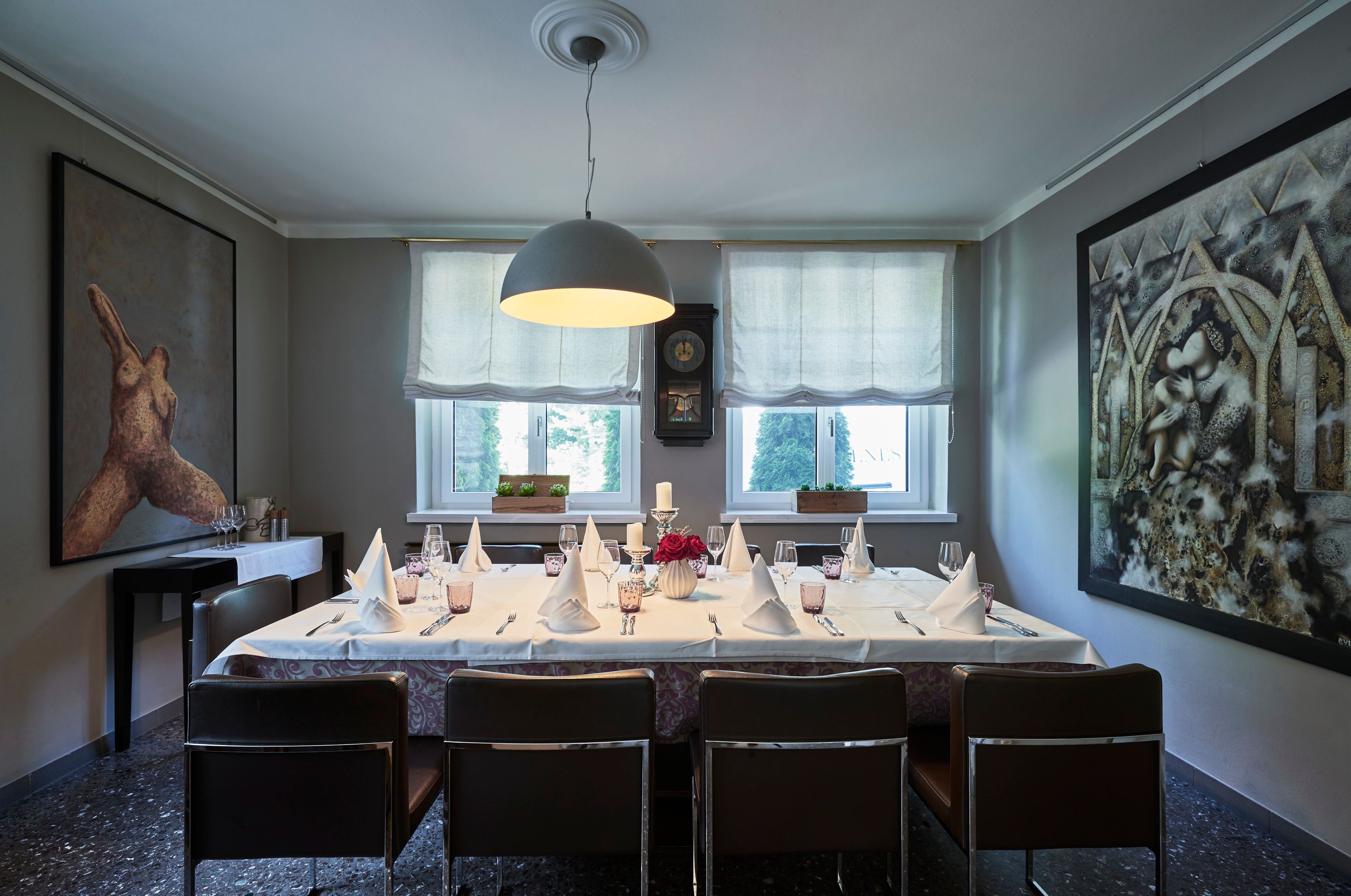 Elegantes Esszimmer mit gedecktem Tisch, Kunstwerken an den Wänden und großen Fenstern.