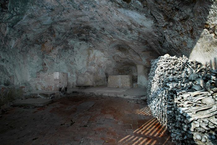 Innenansicht einer Höhlenkirche mit Knochenstapel an der Wand.