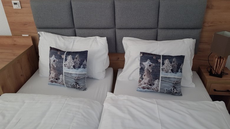 Doppelzimmer mit zwei Einzelbetten, grauem Kopfteil, graue Kissen und wei&szlig;er Bettw&auml;sche