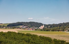 Landschaftsansicht von Gro&szlig;ru&szlig;bach mit Kirche und H&uuml;geln im Hintergrund.