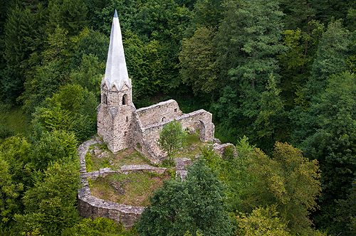 Luftaufnahme einer alten Burgruine im Wald mit einem spitzen Turm.