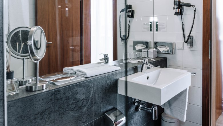 Modernes Hotelbadezimmer mit Waschbecken, Spiegel und Handt&uuml;chern.