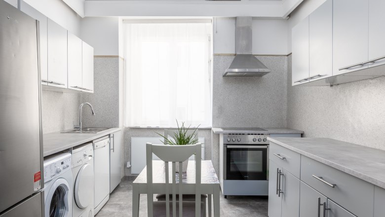 Moderne K&uuml;che mit Waschmaschine, Herd und Tisch mit Stuhl.