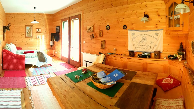 Gem&uuml;tlicher Raum in einer Holzh&uuml;tte mit Sofa, Tisch und Dekorationen.