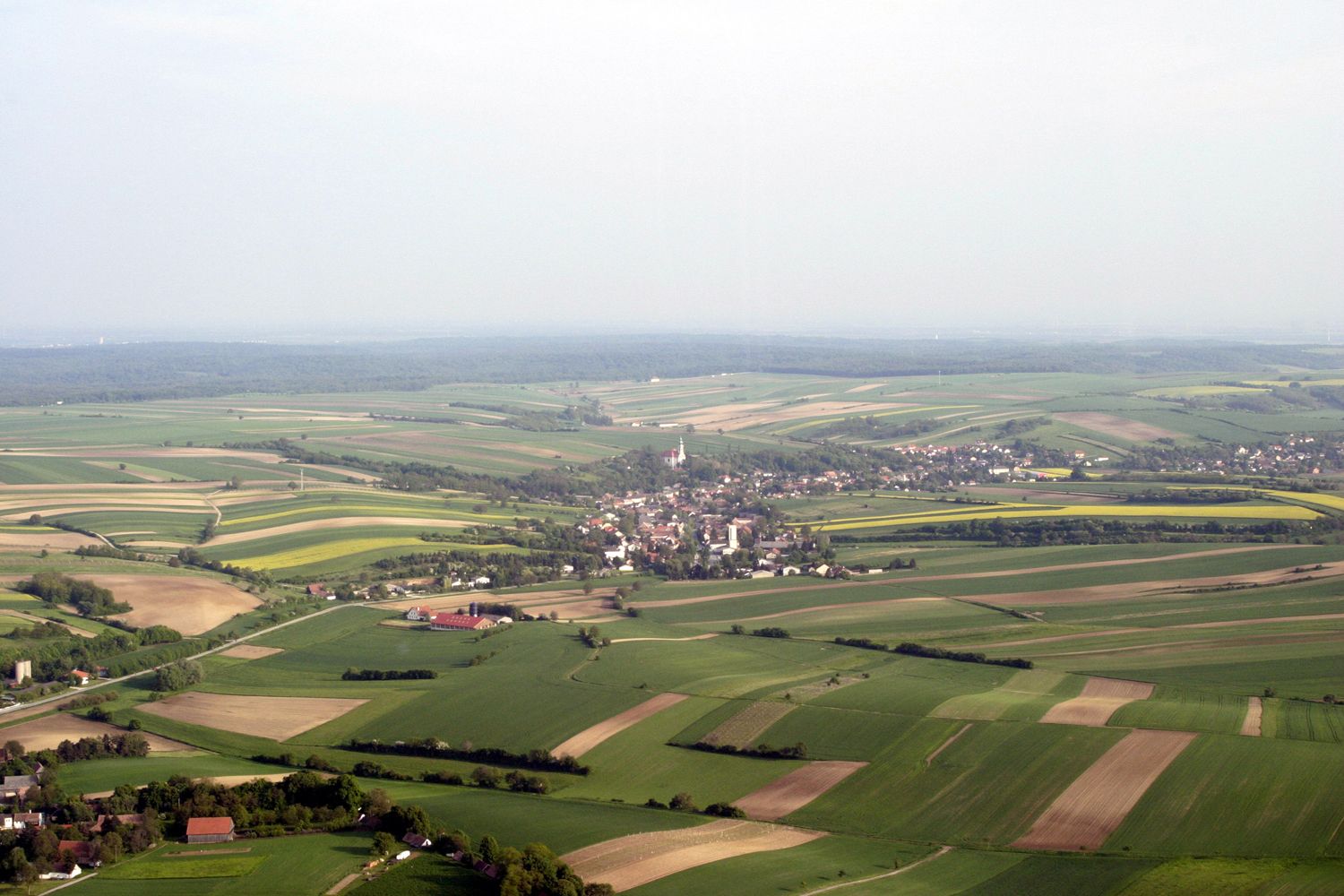 Luftaufnahme von Hochleithen, umgeben von Feldern und Wäldern.