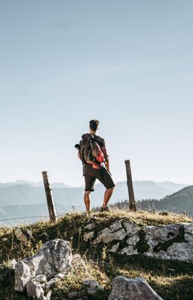 Die sanften Hügel der Ybbstaler Alpen erstrecken sich majestätisch im Hintergrund, während ein Wanderer inmitten der Natur verweilt. Die klare Luft und die atemberaubende Aussicht laden dazu ein, die Seele baumeln zu lassen und die Schönheit der Berglandschaft zu genießen.