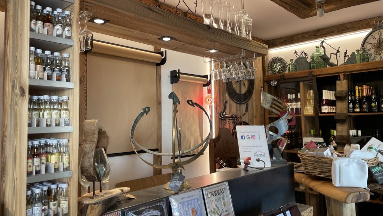 Innenansicht eines rustikalen Ladens mit Spirituosen, Gläsern und Dekorationsartikeln.