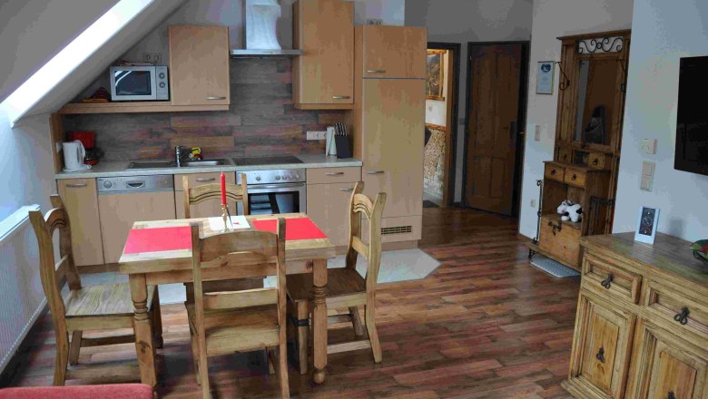 Gem&uuml;tliche Ferienwohnungsk&uuml;che mit Holzm&ouml;beln und Esstisch.