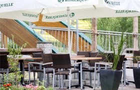 Gemütliche Terrasse mit Tischen, Stühlen und Sonnenschirmen.