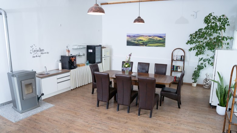 Gem&uuml;tlicher Raum mit Esstisch, St&uuml;hlen, Pflanzen und K&uuml;chenzeile.