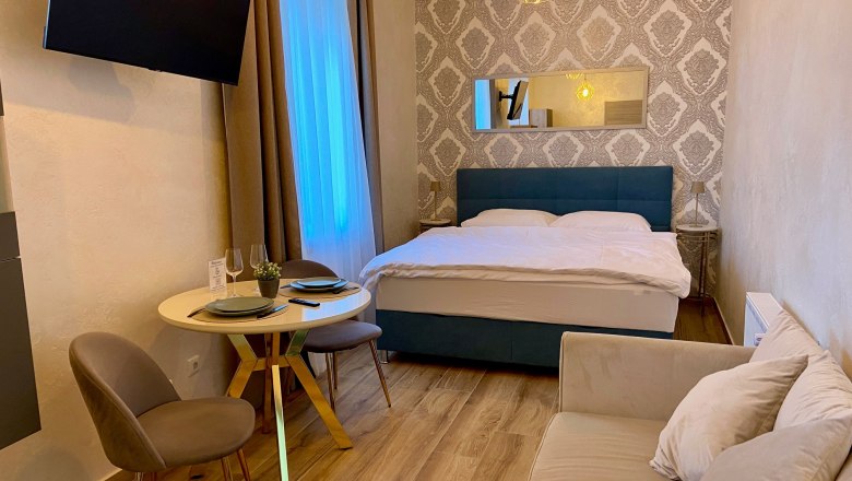 Ein gemütliches Hotelzimmer mit Doppelbett, kleinem Esstisch und Sofa.