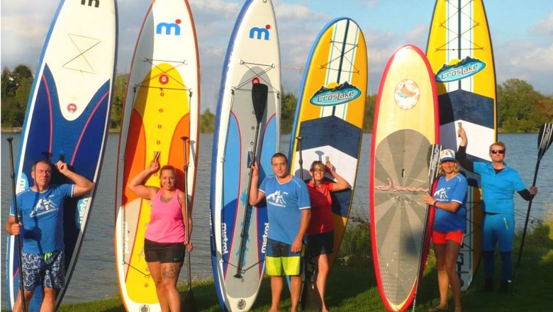Gruppe von Menschen mit Stand-Up-Paddle-Boards am See.