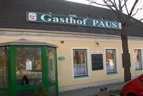 Außenansicht eines Gasthofs mit gelber Fassade und grünem Schild 'Gasthof Paus'.