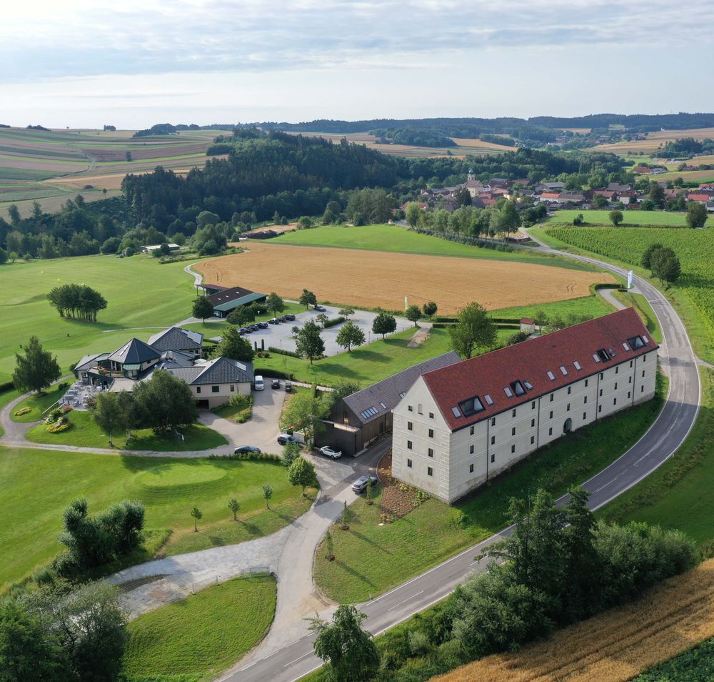 Luftaufnahme eines Landguts mit Golfplatz, Feldern und Gebäuden in einer ländlichen Umgebung.