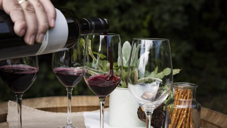 Hand gie&szlig;t Rotwein in Gl&auml;ser