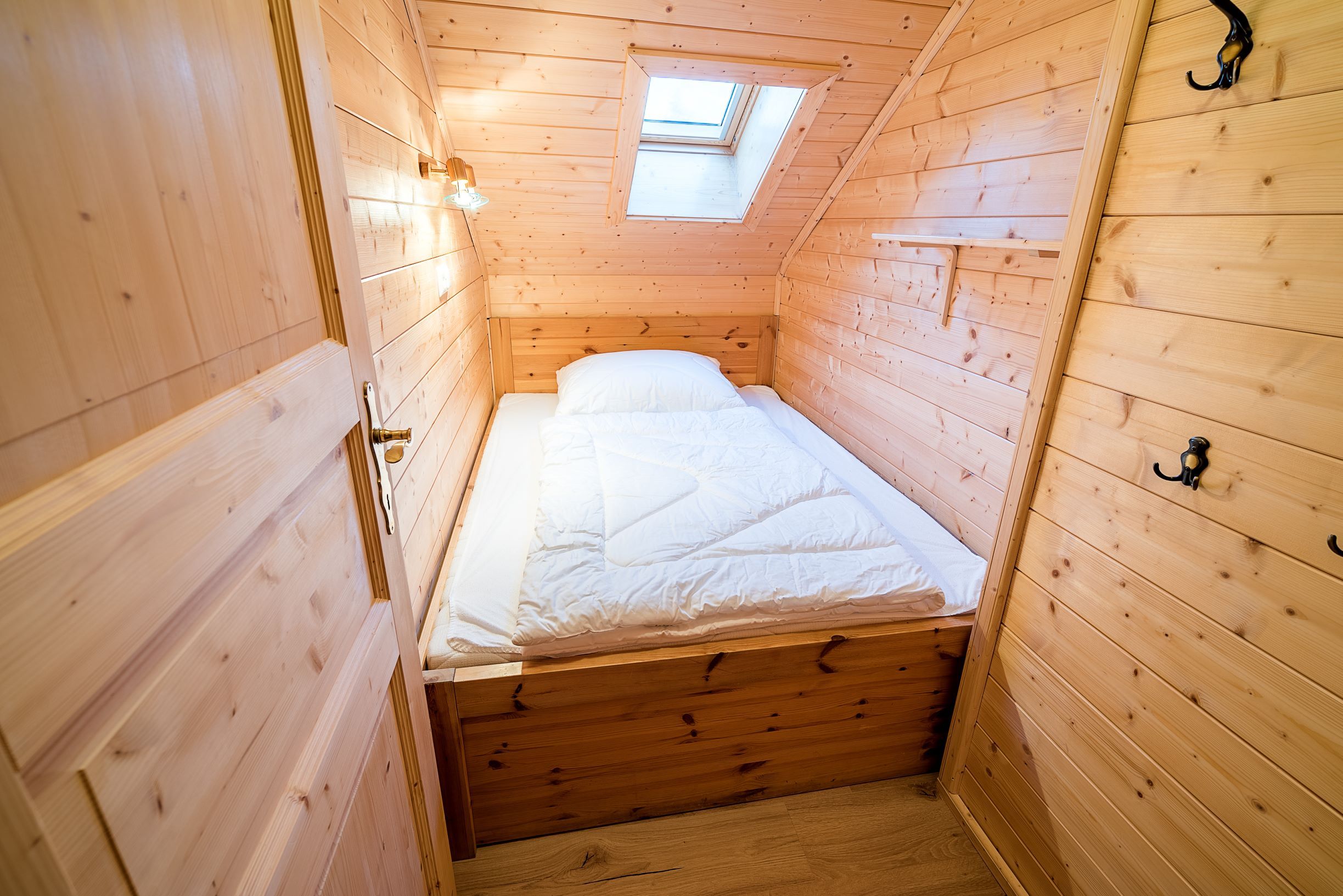 Kleines Kinderzimmer mit Holzverkleidung, Einzelbett und Dachfenster.