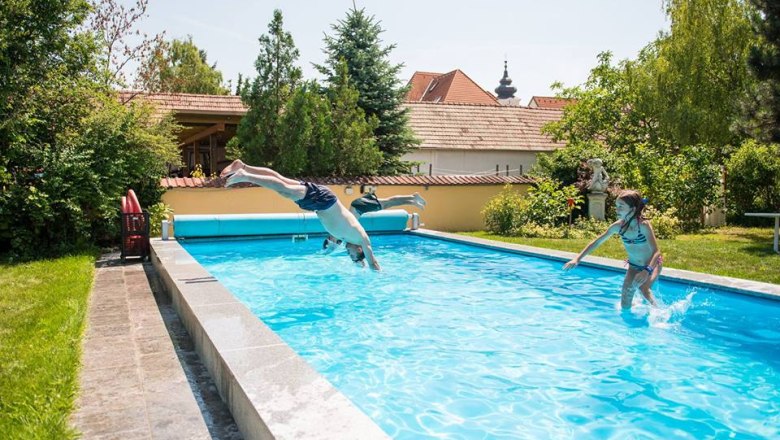 Kinder spielen in einem Swimmingpool auf einem Winzerhof.