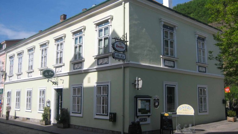 Historisches Gebäude mit grüner Fassade und mehreren Fenstern, beschildert als Gasthaus.