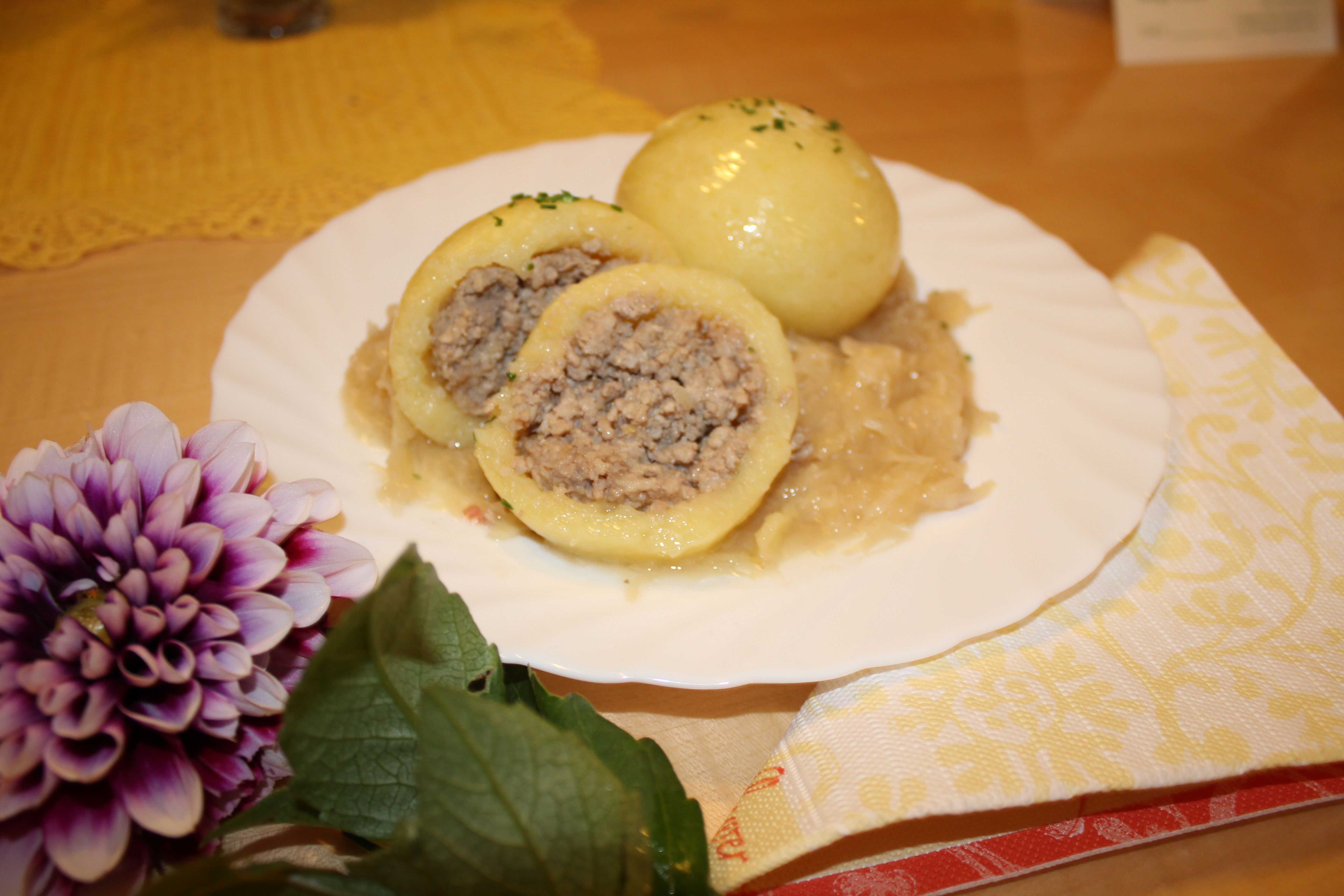 Ein Teller mit Waldviertler Fleischknödeln auf Sauerkraut, dekoriert mit einer Blume.