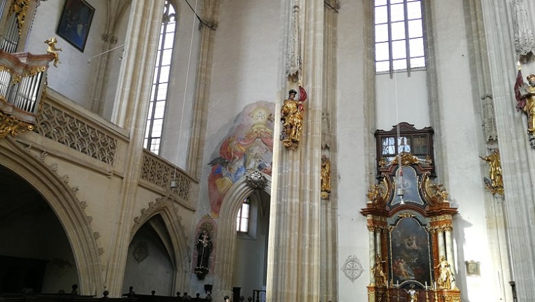 Innenansicht der Piaristenkirche mit Altar, Fresken und hohen Fenstern.