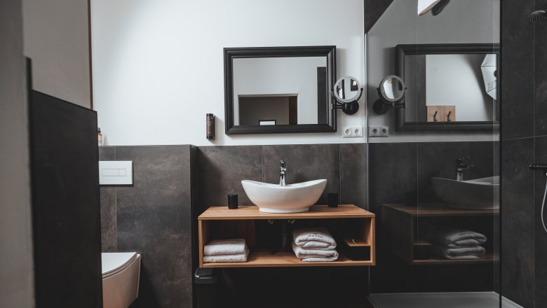 Modernes Badezimmer mit Waschbecken, Spiegel, Toilette und Dusche.