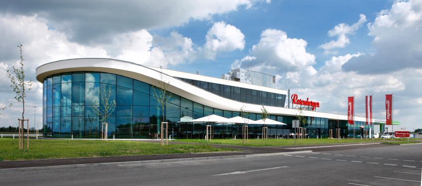 Modernes Gebäude mit Glasfassade und geschwungenem Dach.