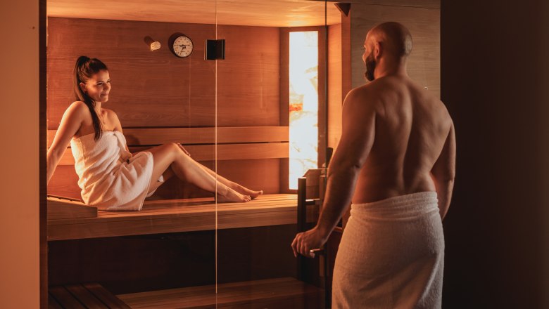 Ein Mann und eine Frau in Handtüchern in einer Sauna.