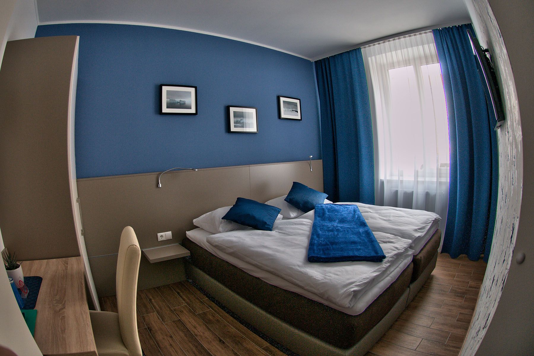 Modernes Gästezimmer mit blauem Akzent, Doppelbett und Schreibtisch.