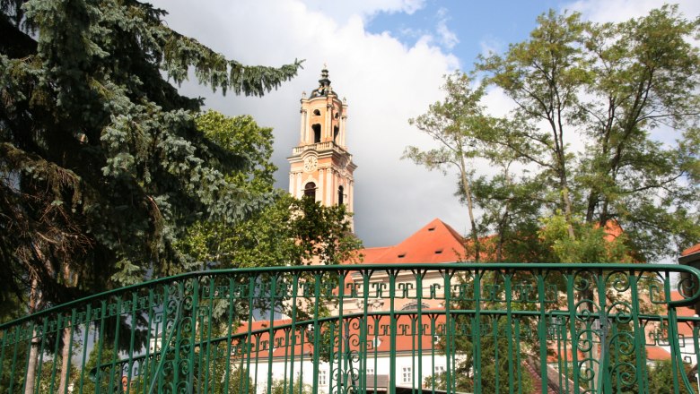 Stift Herzogenburg mit Turm und gr&uuml;nem Zaun im Vordergrund.
