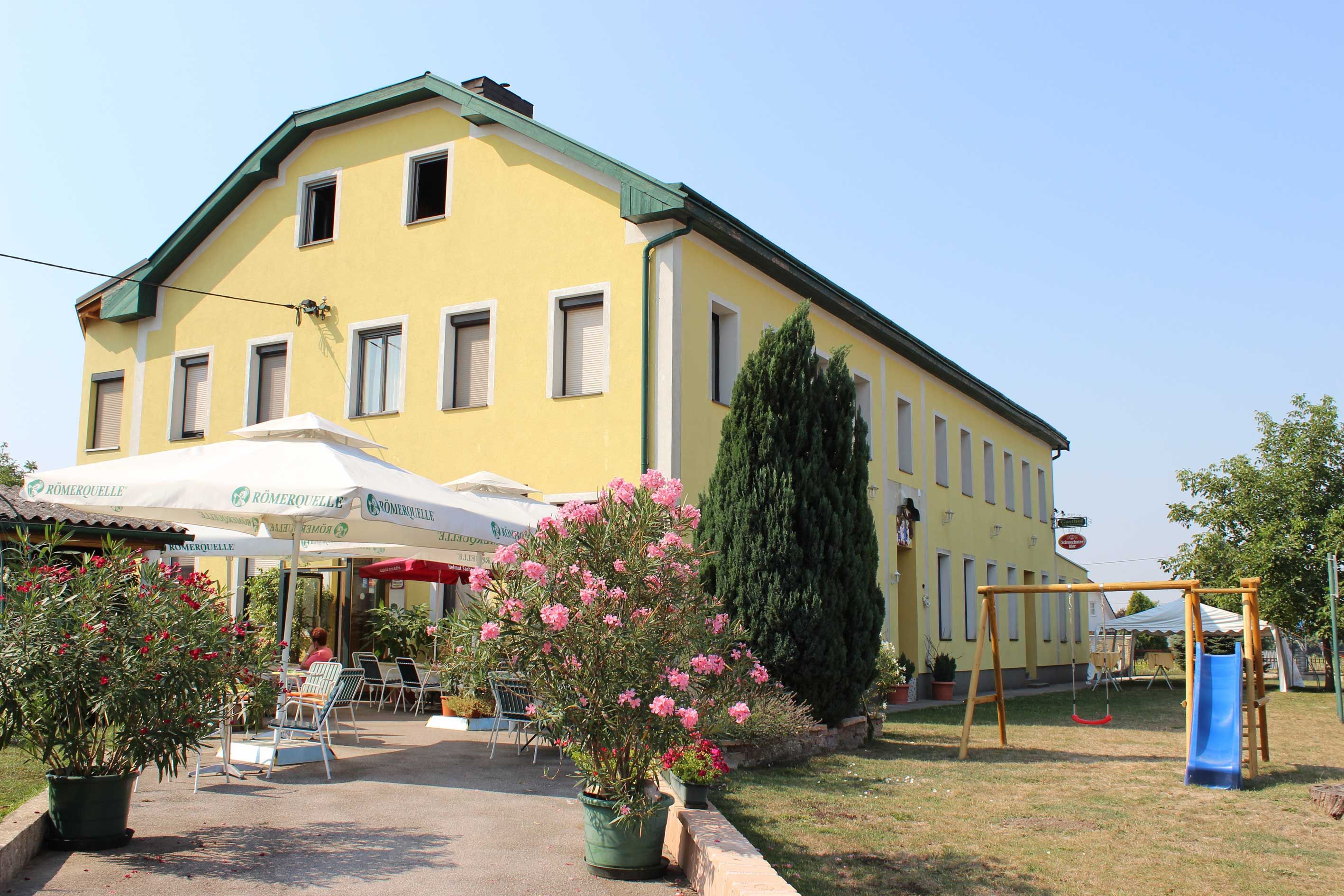 Gelbes Gebäude mit Terrasse und Spielplatz im Vordergrund.