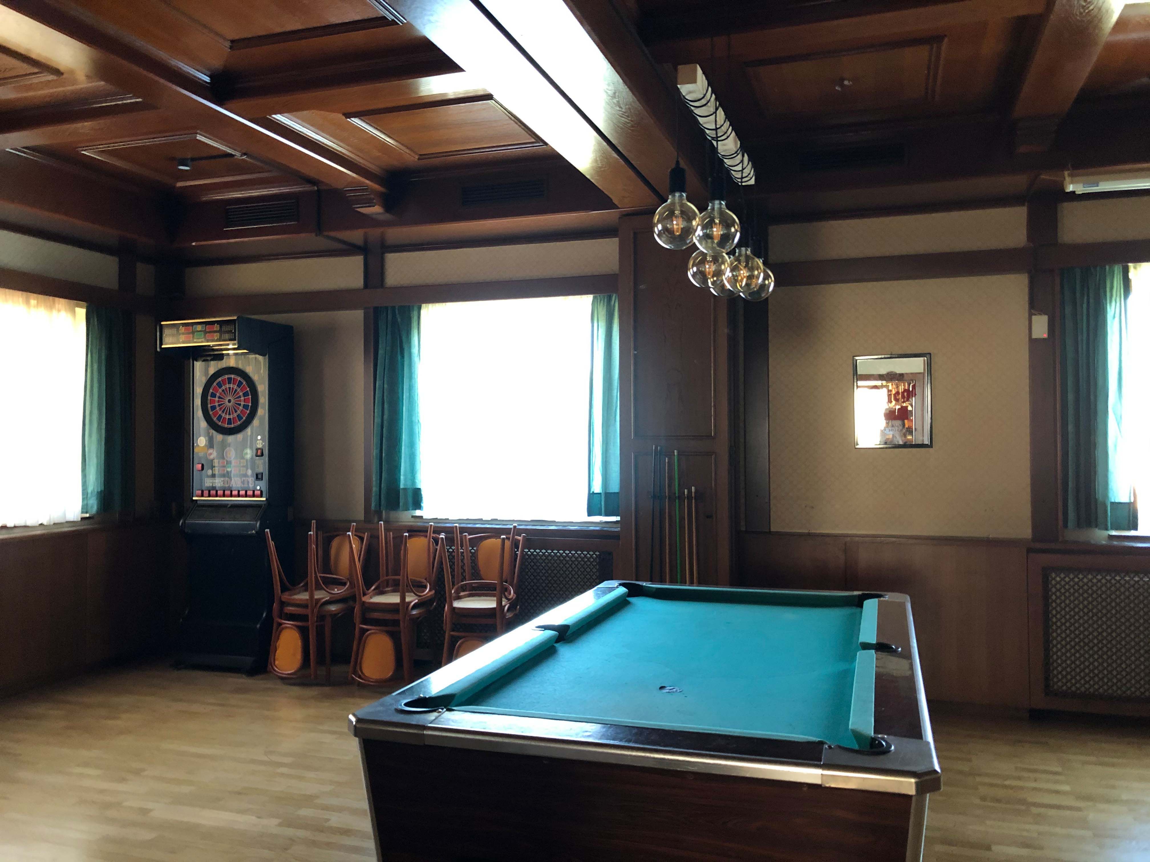 Innenansicht eines Gasthauses mit Billardtisch und Dartautomat.