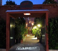 Eingang zu einem Innenhof mit beleuchtetem Weg und Pflanzen.