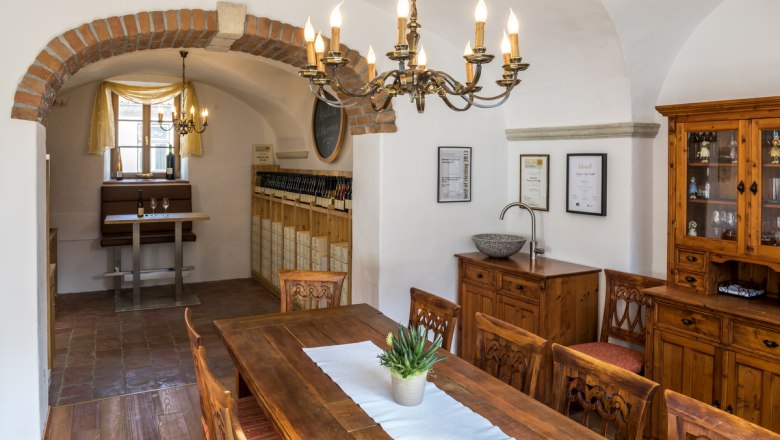 Gem&uuml;tlicher Raum mit Holzm&ouml;beln, Kronleuchter und Weinregal.