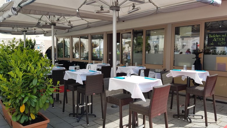 Au&szlig;enbereich eines Restaurants mit gedeckten Tischen und Sonnenschirmen.