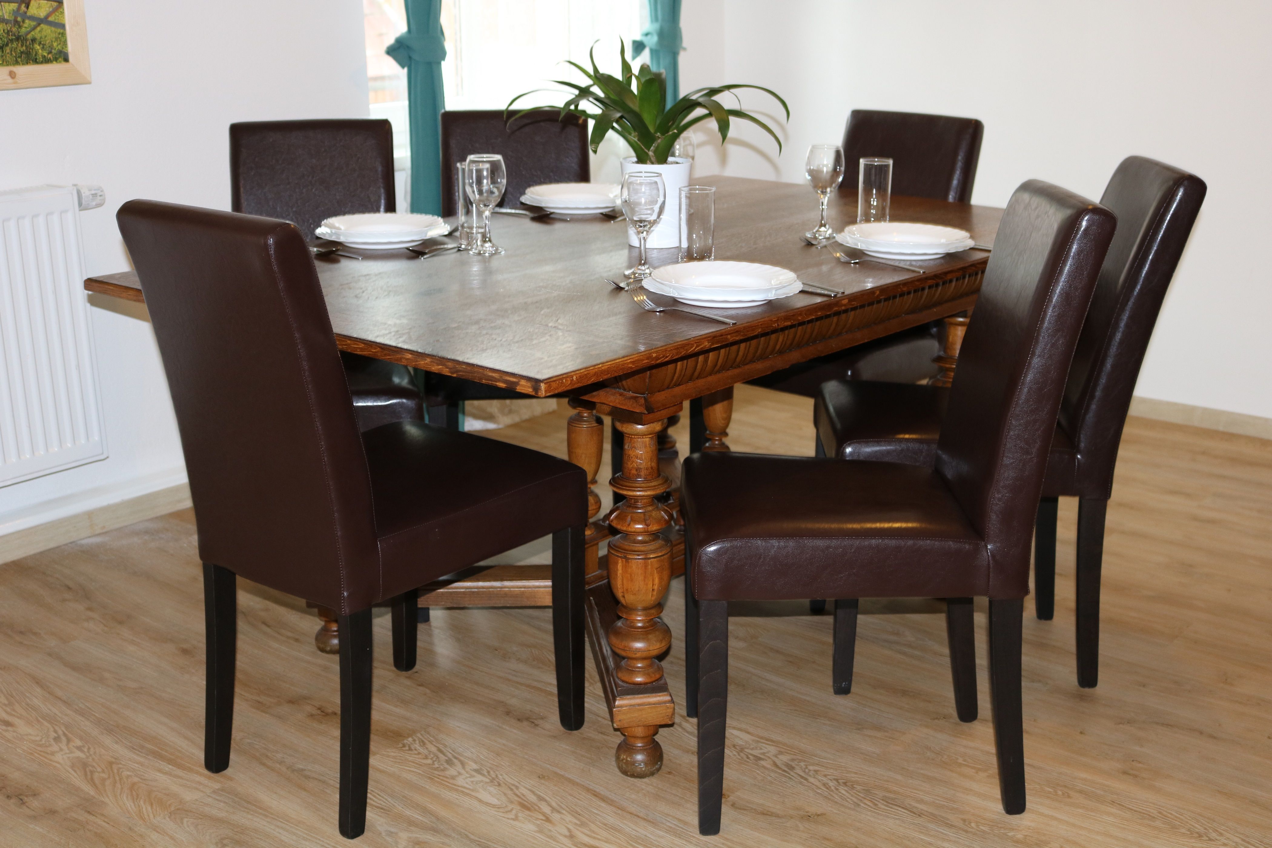 Essbereich mit Holztisch und sechs braunen Stühlen, gedeckt für sechs Personen.