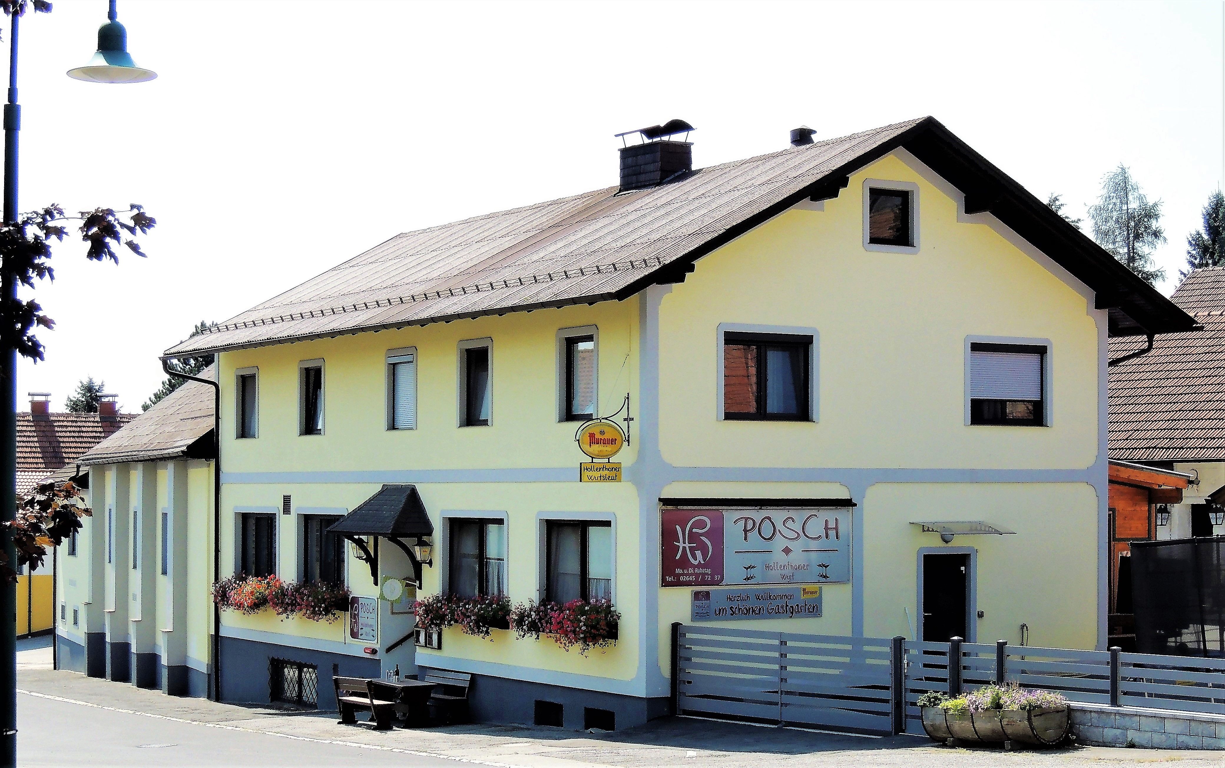 Gelbes Gasthaus mit Blumenkästen und Schild 'Posch'.